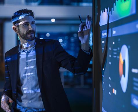 Man standing by large screen giving a presentation